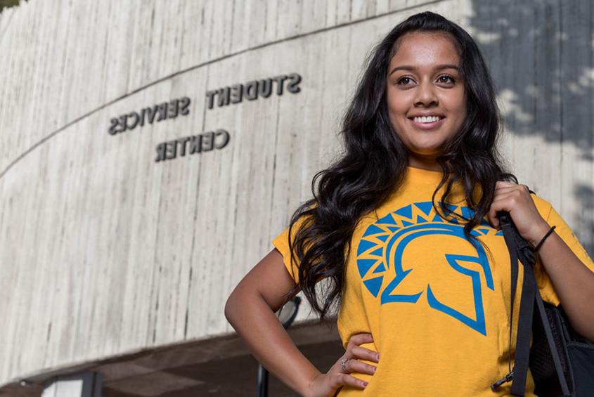 A student standing in front of the services building.